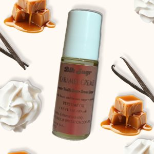 A bottle of Blk Sugr “Caramel Crème” perfume oil placed on a creamy beige background, surrounded by melting caramel cubes, vanilla beans, and whipped cream. The label notes include caramel, vanilla bean, and brown sugar.