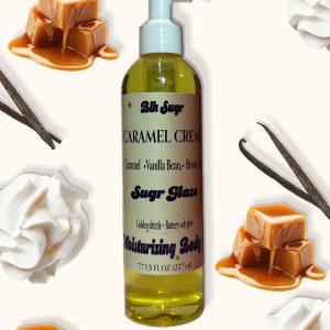 A bottle of Blk Sugr “Caramel Crème” Sugr Glaze body oil on a cream background, surrounded by whipped cream, vanilla beans, and dripping caramel pieces. The label highlights caramel, vanilla bean, and brown sugar notes.