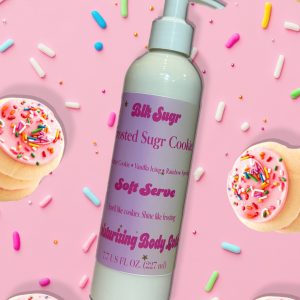 A bottle of Blk Sugr Frosted Sugr Cookie Soft Serve Lotion on a pink sprinkle background, surrounded by cookies, icing, and rainbow sprinkles.