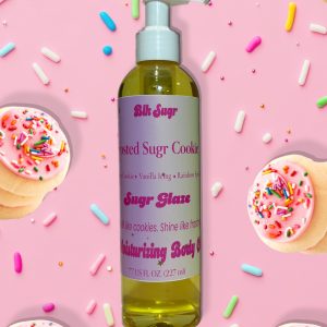 A bottle of Blk Sugr “Frosted Sugr Cookie” Sugr Glaze body oil on a pink background, surrounded by pink-iced sugar cookies and colorful rainbow sprinkles. The label highlights sugar cookie, vanilla icing, and rainbow sprinkles.