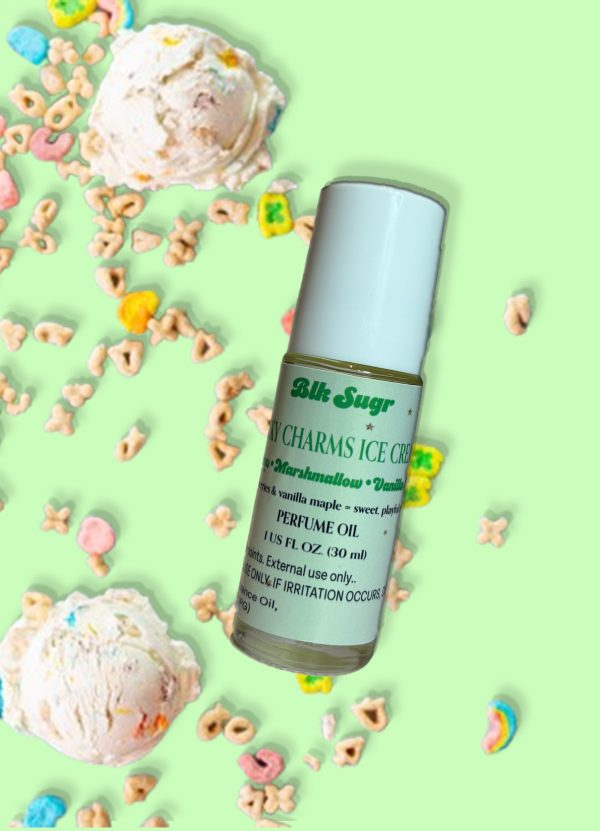 A bottle of Blk Sugr “Lucky Charms Ice Cream” perfume oil on a mint green background, surrounded by scoops of ice cream and colorful cereal pieces resembling marshmallow shapes. The label includes notes of cereal, marshmallow, and vanilla maple.