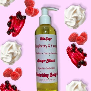 A bottle of Blk Sugr “Raspberry & Creme” Sugr Glaze body oil on a pink background, surrounded by whipped cream, raspberries, and berry sauce drizzle.