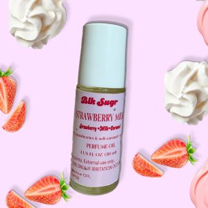 A bottle of Blk Sugr “Strawberry Milk” perfume oil on a light pink background, surrounded by whipped cream swirls and fresh strawberry slices. The label highlights strawberry, milk, and caramel notes