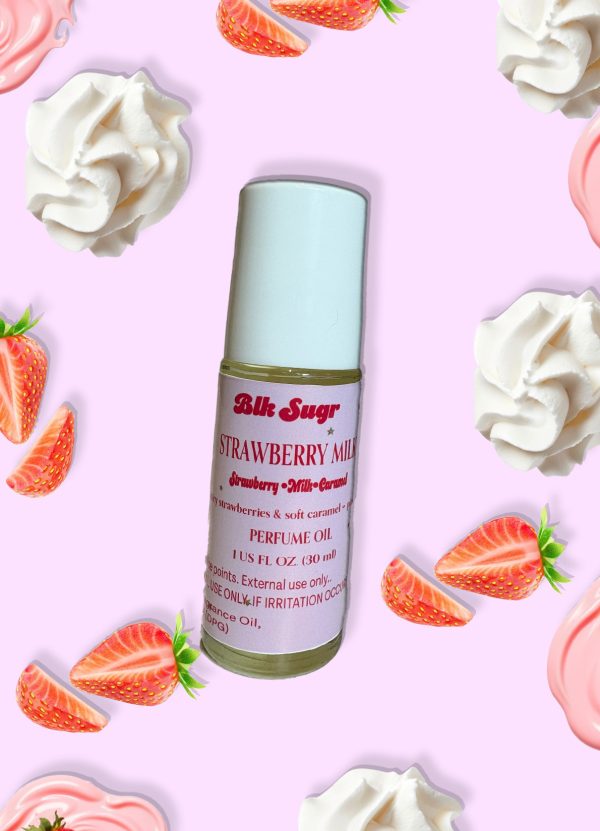 A bottle of Blk Sugr “Strawberry Milk” perfume oil on a light pink background, surrounded by whipped cream swirls and fresh strawberry slices. The label highlights strawberry, milk, and caramel notes