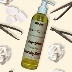 A bottle of Blk Sugr “Warm Vanilla Bean” Sugr Glaze body oil on a cream background with whipped cream, vanilla beans, and Whipped Cream.