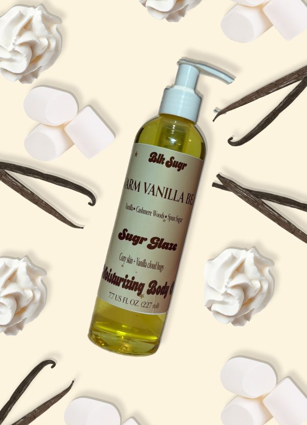 A bottle of Blk Sugr “Warm Vanilla Bean” Sugr Glaze body oil on a cream background with whipped cream, vanilla beans, and Whipped Cream.