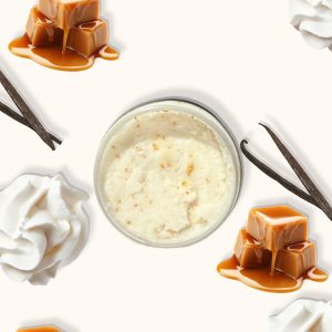 A jar of Blk Sugr Caramel Vanilla Swirl Sugr Buff surrounded by caramel drizzle, whipped cream, and vanilla bean pods on a creamy beige background.