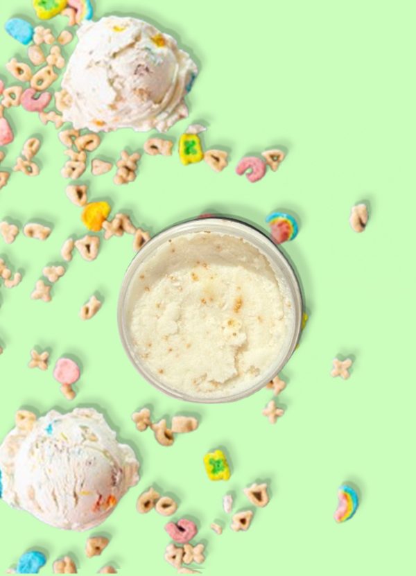 A jar of Blk Sugr Lucky Charms Ice Cream Sugr Buff surrounded by scoops of cereal ice cream and colorful cereal marshmallows on a mint green background.