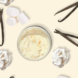 A jar of Blk Sugr Vanilla Marshmallow Creme Sugr Buff surrounded by marshmallows, whipped cream, and vanilla bean pods on a creamy beige background.