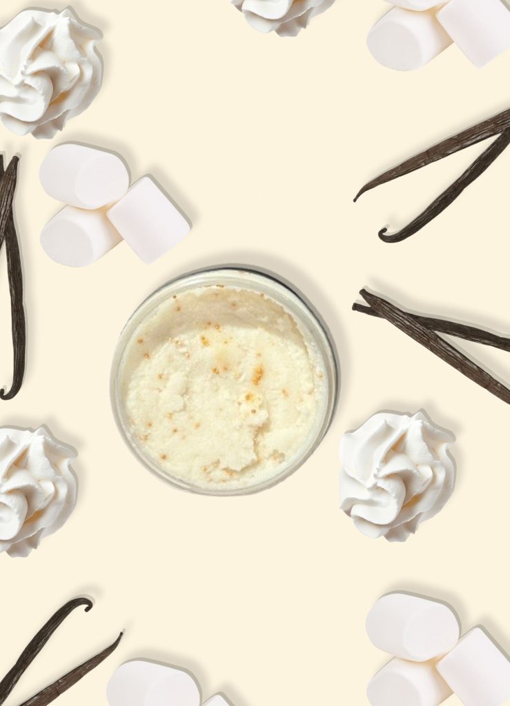 A jar of Blk Sugr Vanilla Marshmallow Creme Sugr Buff surrounded by marshmallows, whipped cream, and vanilla bean pods on a creamy beige background.