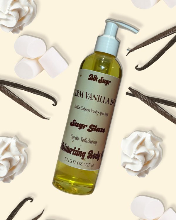 Blk Sugr Warm Vanilla Bean moisturizing body oil with pump, surrounded by whipped cream, vanilla beans, and marshmallows on a cream background.